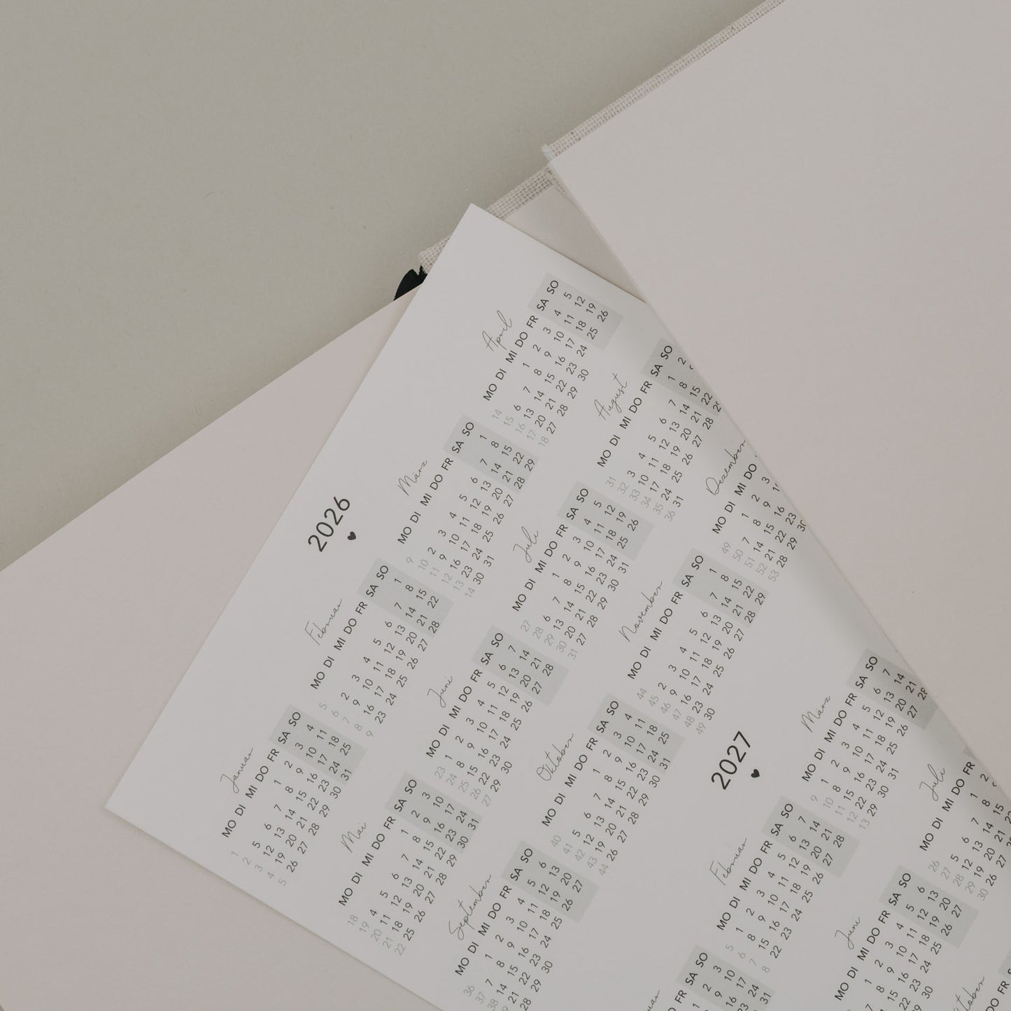 Jahresübersicht 2026 und 2027 des Kalenders „Neues Glück“ auf losem Einlegeblatt in sanften Farben.