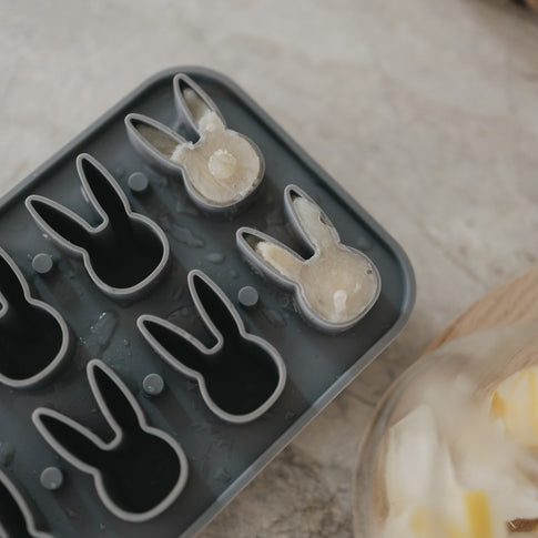 Ansicht von oben der grauen Eiswürfelform aus Silikon mit erhöhten Hasenformen, 2 davon gefüllt mit Eis.