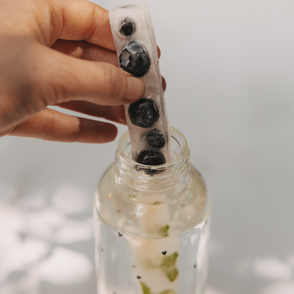 Hand hält Eiswürfel Stick mit Blaubeeren, passend für Glasflaschen und aromatisierte Getränke