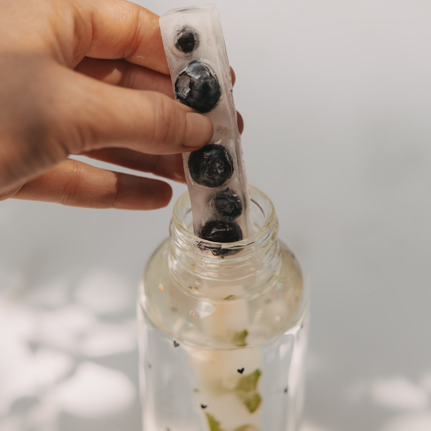Hand hält Eiswürfel Stick mit Blaubeeren, passend für Glasflaschen und aromatisierte Getränke