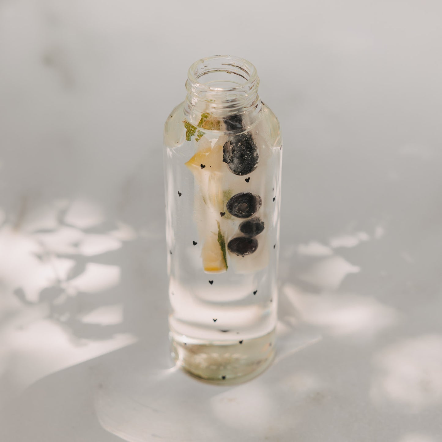 Glasflasche mit Wasser, Minze, Zitrone und Eiswürfel Stick mit Beeren für erfrischende Drinks