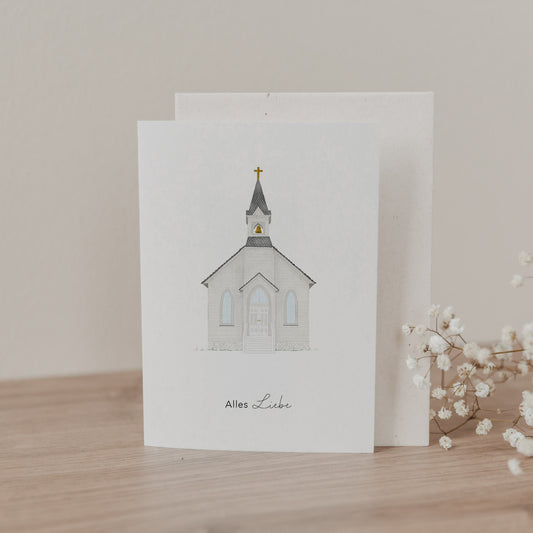 Klappkarte mit handgezeichneter Kirche und Schrift „Alles Liebe“, stehend mit Umschlag auf Holzoberfläche neben Trockenblumen.