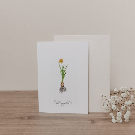 Klappkarte mit gelber Narzisse auf weißem Hintergrund, zarte Frühlingsillustration mit Wurzelmotiv und beigem Umschlag.