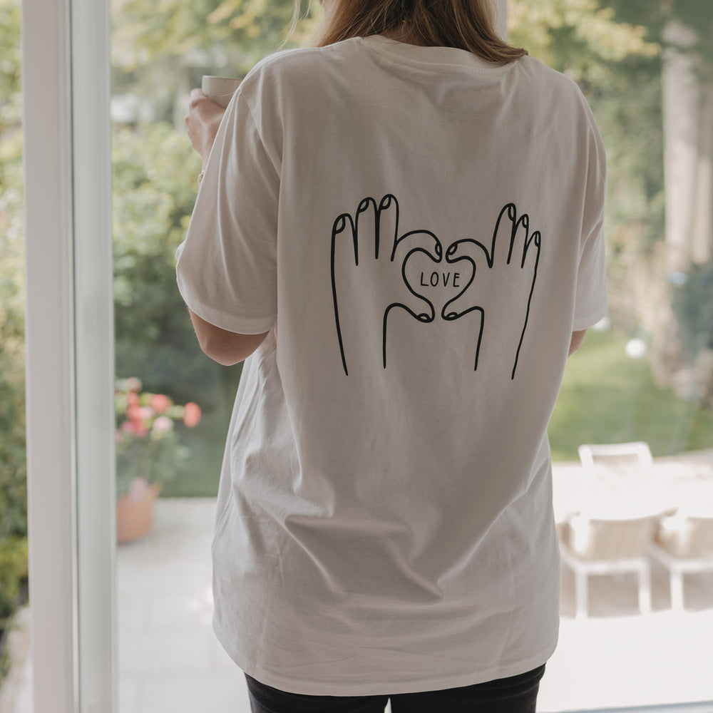 Rückenansicht des LOVE-T-Shirts vor einem Fenster mit Gartenblick