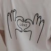 Close-up Rückenansicht LOVE Shirt mit schwarzem Herz-Hand-Motiv auf Weiß