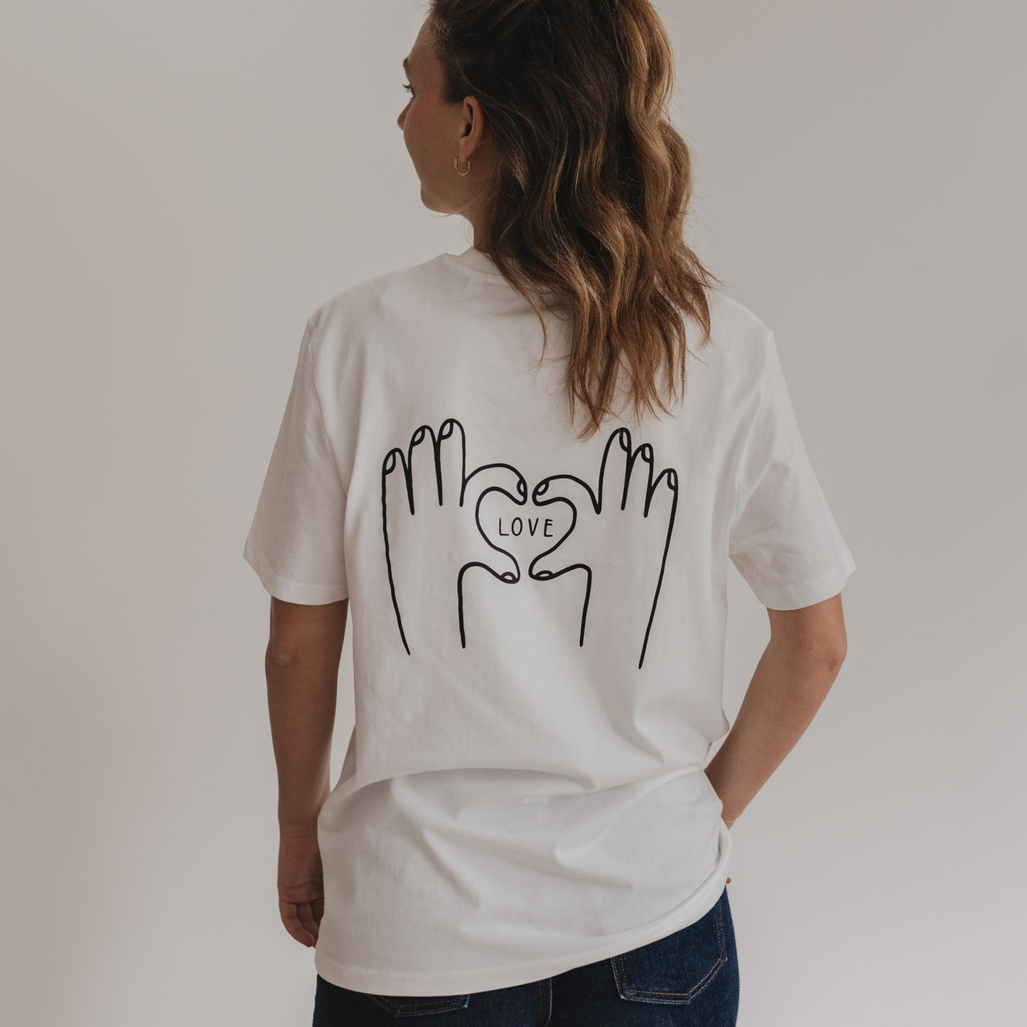 Rückenansicht LOVE Shirt mit Herz-Hand-Motiv bei Frau mit lockigem Haar