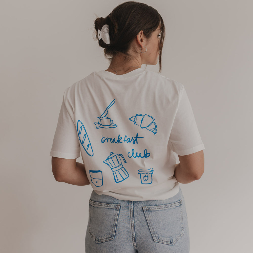 Rückseite des weißen Breakfast Club T-Shirts mit blauen Illustrationen von Frühstücksmotiven und Schriftzug.
