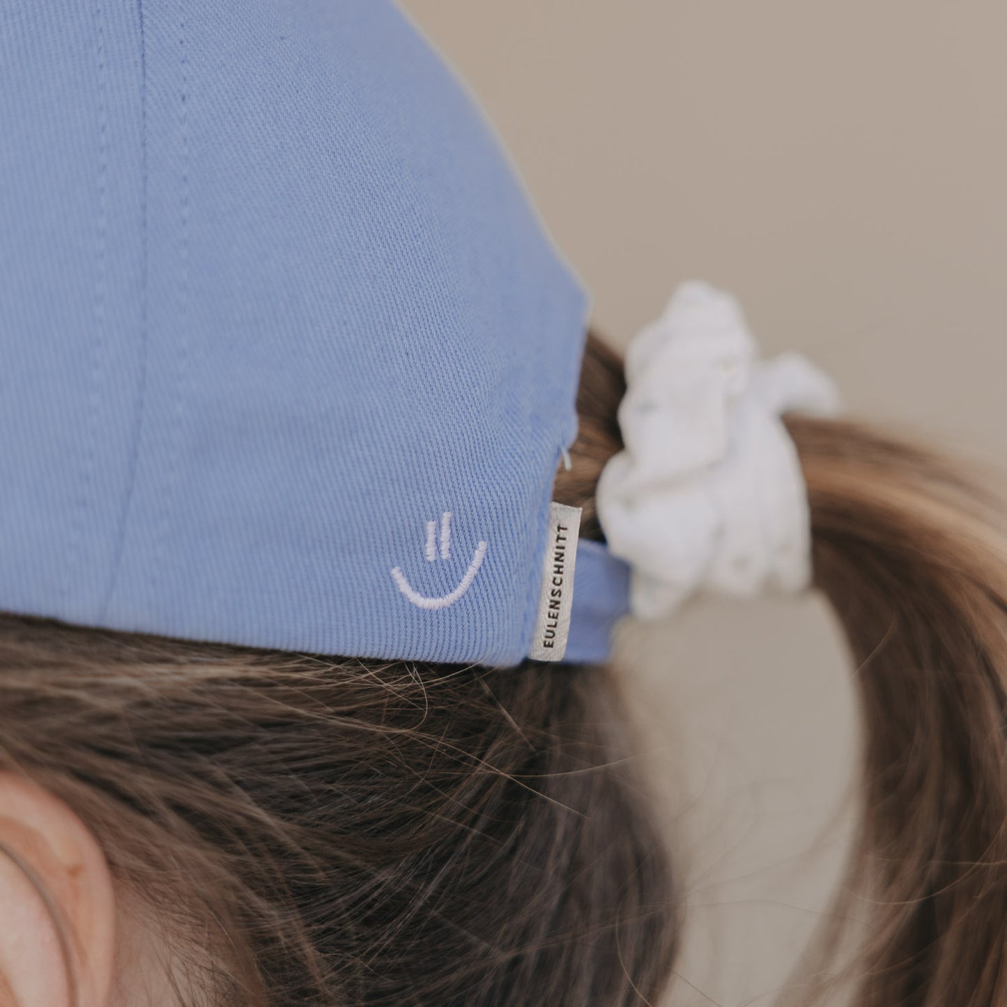 Detailansicht hellblaue Cap mit Smiley-Stickerei an der Rückseite