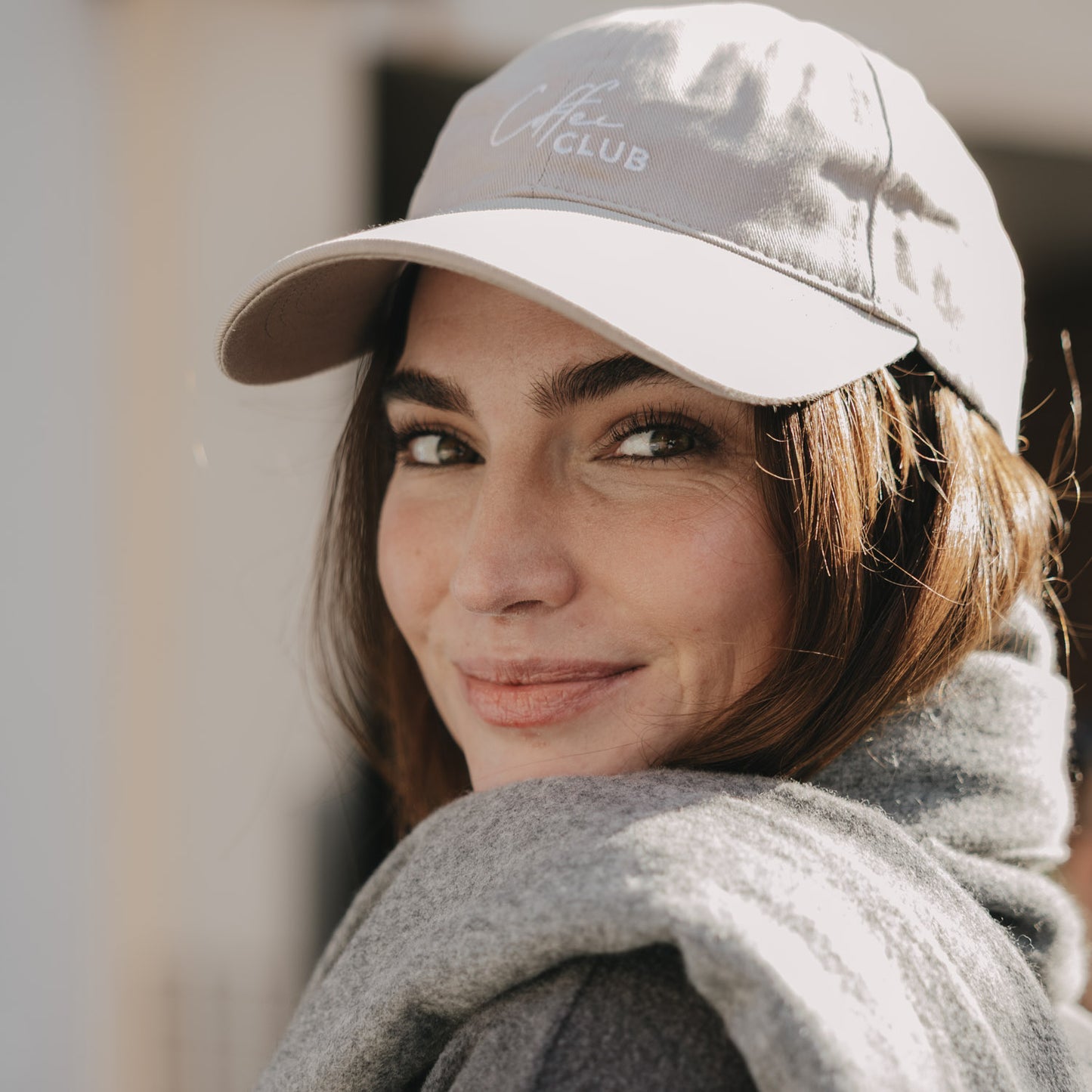 Frau trägt taupefarbene Cap mit weißer Stickerei „Coffee Club“