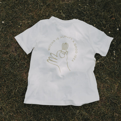 Weißes Matcha T-Shirt flach auf Gras liegend, mit Print im Fokus