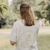 Frau trägt weißes Matcha T-Shirt und hält Getränk im Park, Rückenansicht