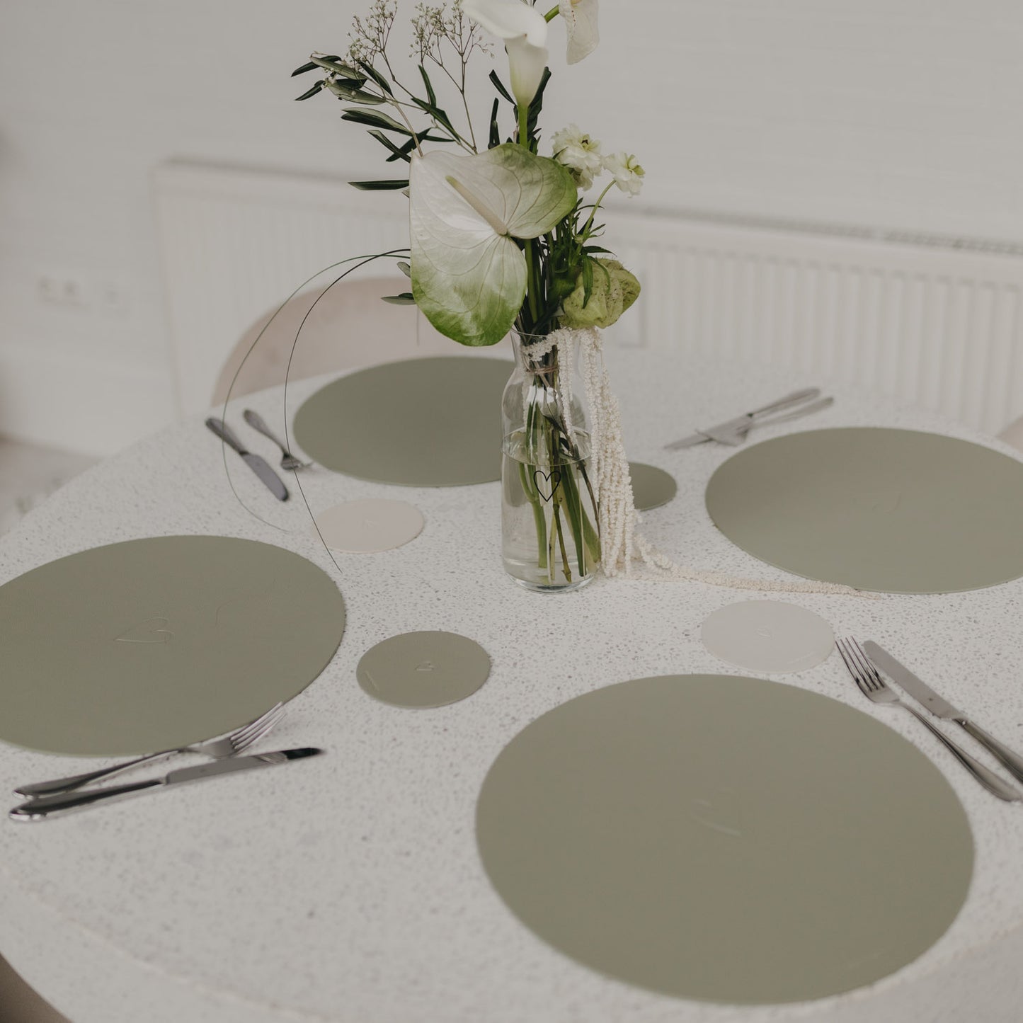 Tischdeko mit mehreren Platzsets Herz Grün in verschiedenen Grüntönen und Blumenarrangement.