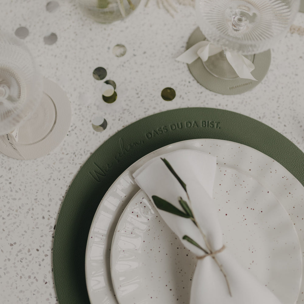 Tischgedeck mit dunkelgrünem Platzset und eingeprägtem Spruch im Detail.