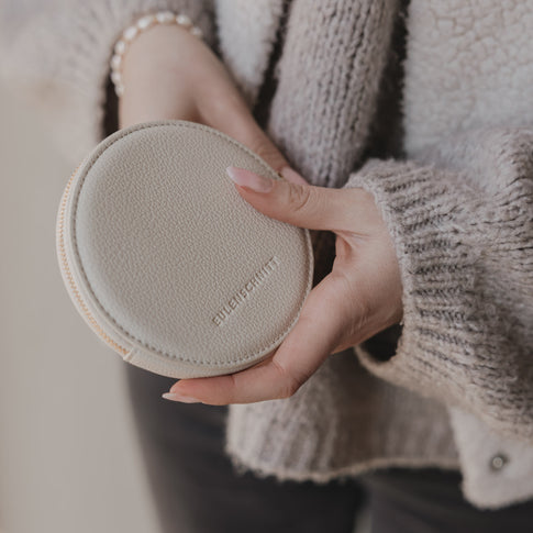 Rückseite des runden Portemonnaies in Creme mit geprägtem Eulenschnitt Schriftzug.“