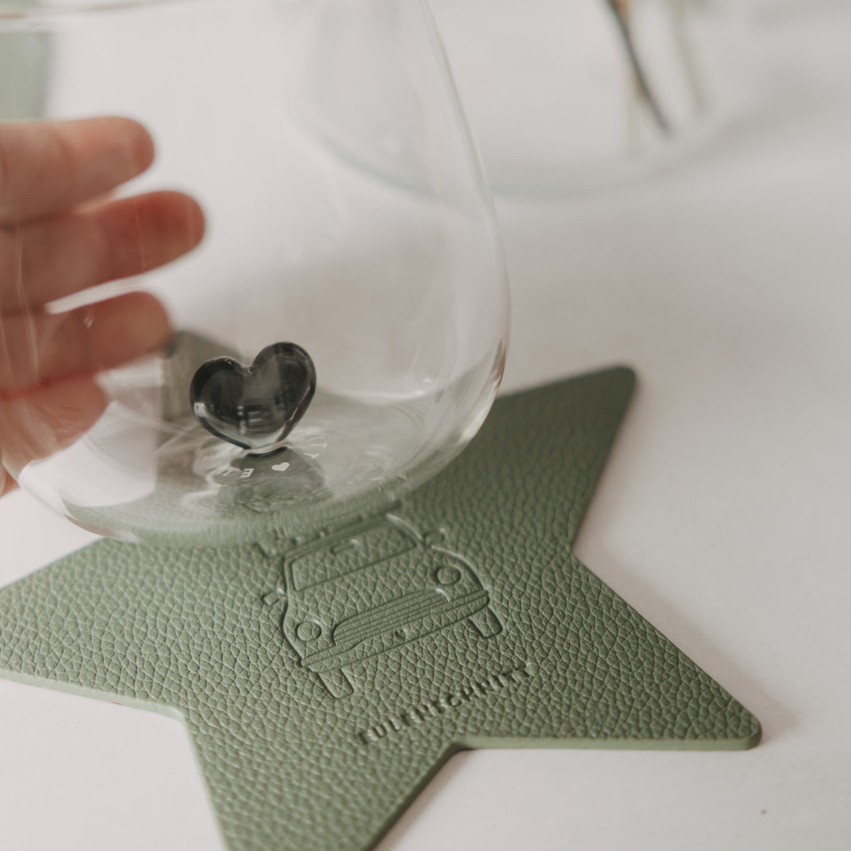 Hellgrüner Stern-Untersetzer mit Auto-Prägung unter einem Glas mit Herzdetail