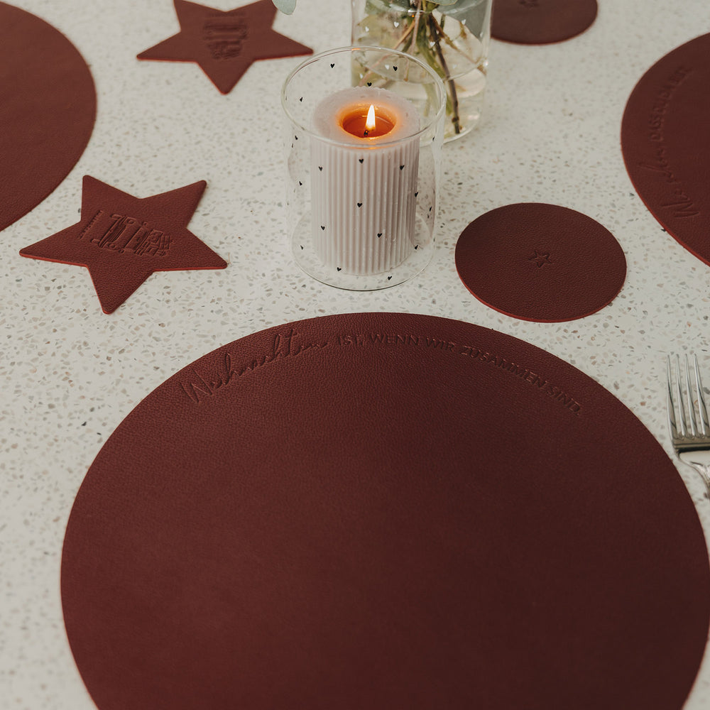 Rotes rundes Weihnachts-Platzset mit Schriftzug auf festlich dekoriertem Esstisch
