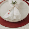 Rotes Weihnachts-Platzset unter Keramikteller mit festlich dekorierter Serviette