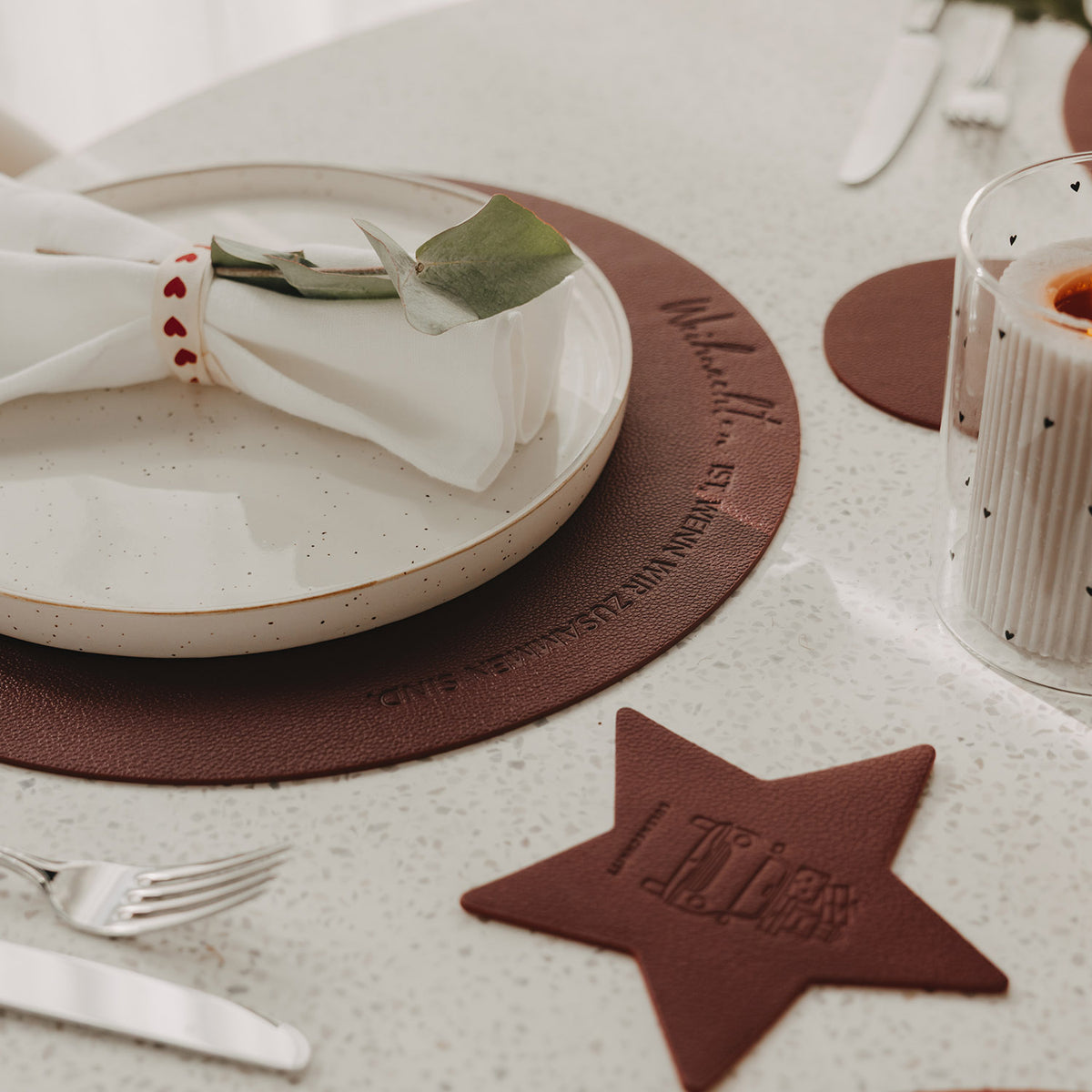 Dunkelrotes Weihnachts-Platzset mit Schriftzug auf festlich gedecktem Tisch