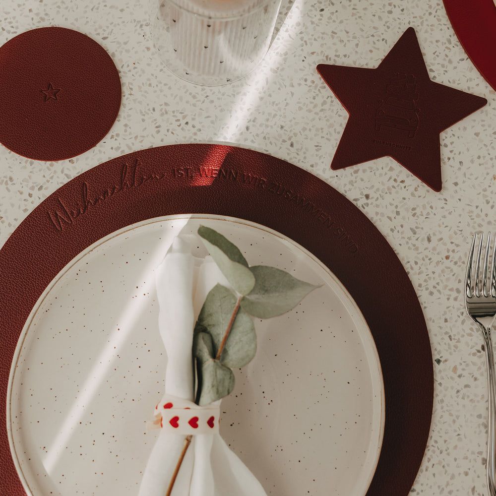 Rundes dunkelrotes Weihnachts-Platzset mit Schriftzug, Teller und Weihnachtsdeko