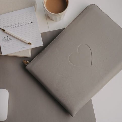 Laptop Sleeve grau mit geprägtem Herz von Eulenschnitt auf Schreibtisch mit Notizblock, Stift und Kaffee