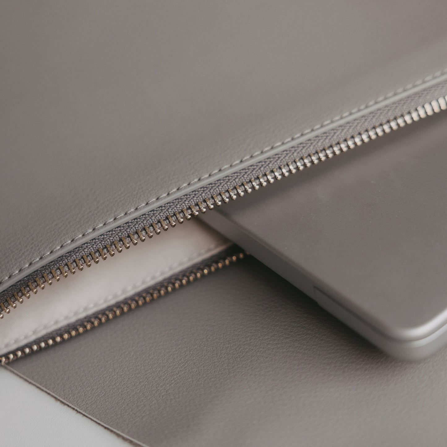 Detail des goldenen Reißverschlusses am grauen Laptop Sleeve mit Herzprägung von Eulenschnitt