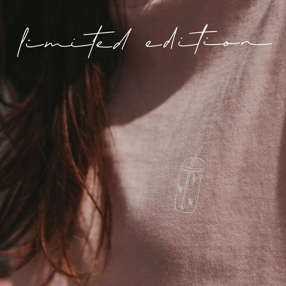 Detailaufnahme des rosafarbenen T-Shirts mit kleinem weißem Iced-Coffee-Motiv auf der Brust.
