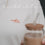 Detailaufnahme des weißen T-Shirts mit kleinem roten „Coffee Lover“-Print auf der Brust und Iced Coffee im Vordergrund.