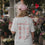 Frau mit rosa Cap und weißem Coffee Lover T-Shirt vor einem Blumengeschäft