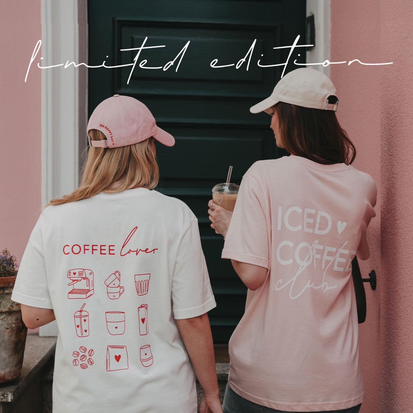 Rückansicht zweier Frauen im weißen „Coffee Lover“- und rosafarbenen „Iced Coffee Club“-T-Shirt vor einer rosa Hauswand.