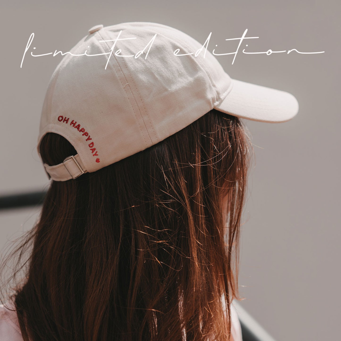 Seitenansicht einer beigen Cap mit roter „Oh Happy Day“-Stickerei