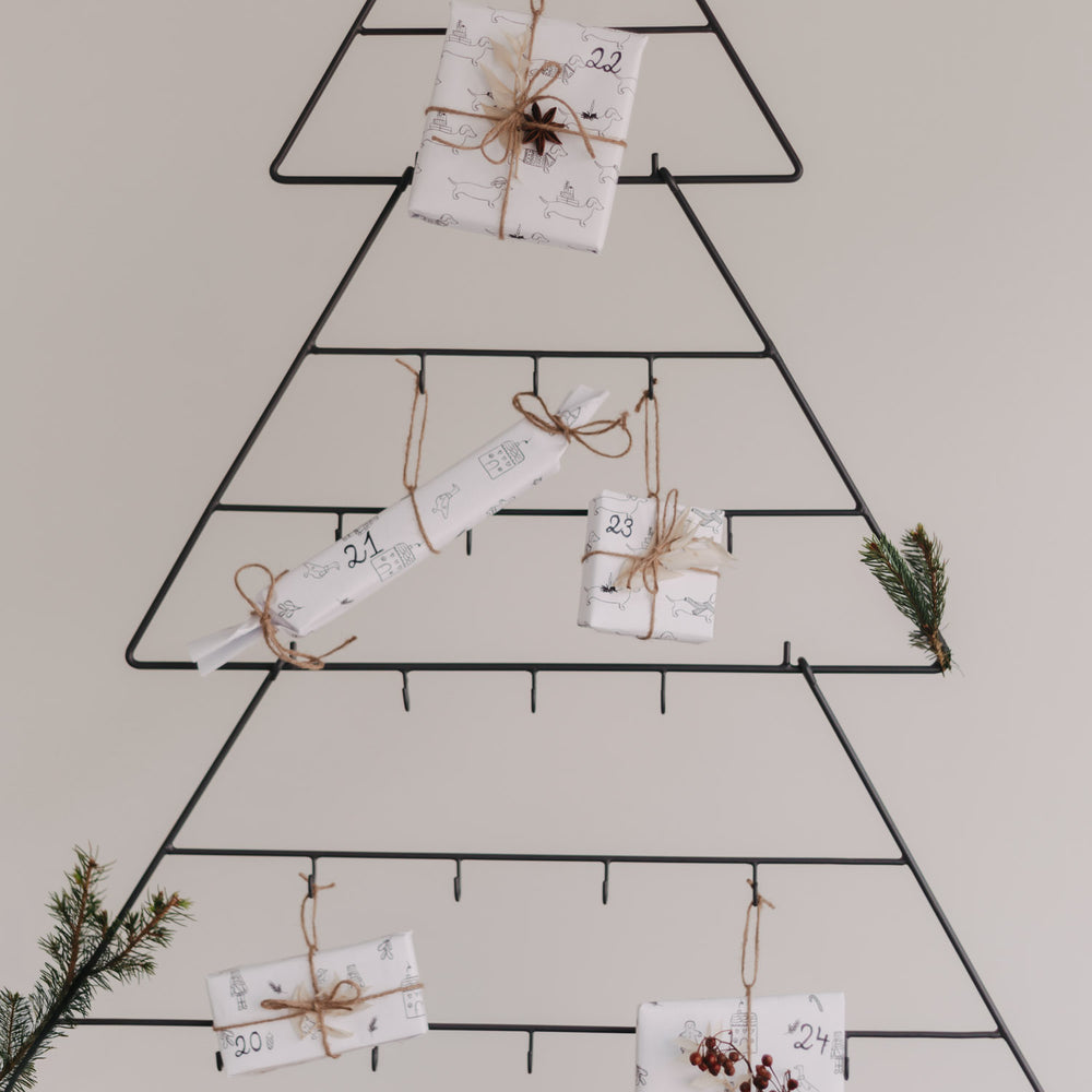 Mehrere Geschenke und Zweige am Adventskalender Tanne dekoriert.