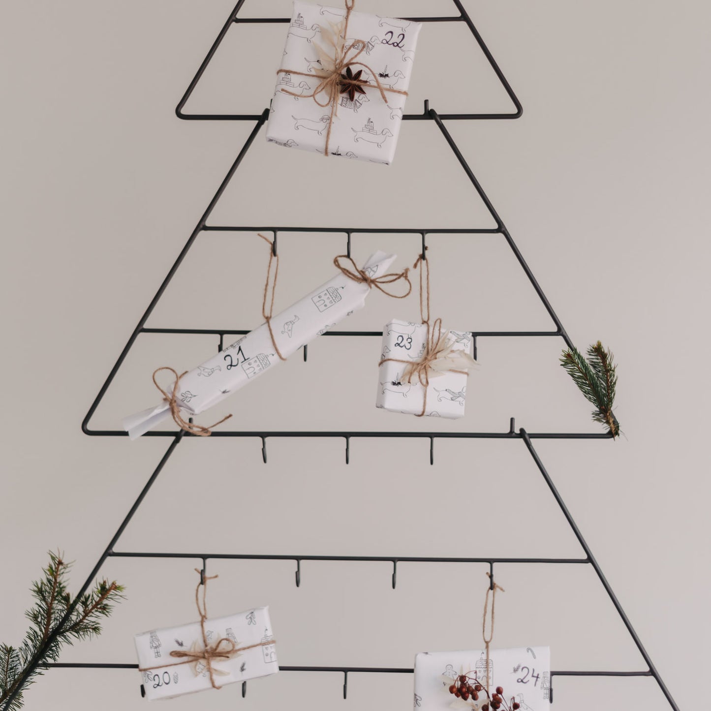 Mehrere Geschenke und Zweige am Adventskalender Tanne dekoriert.