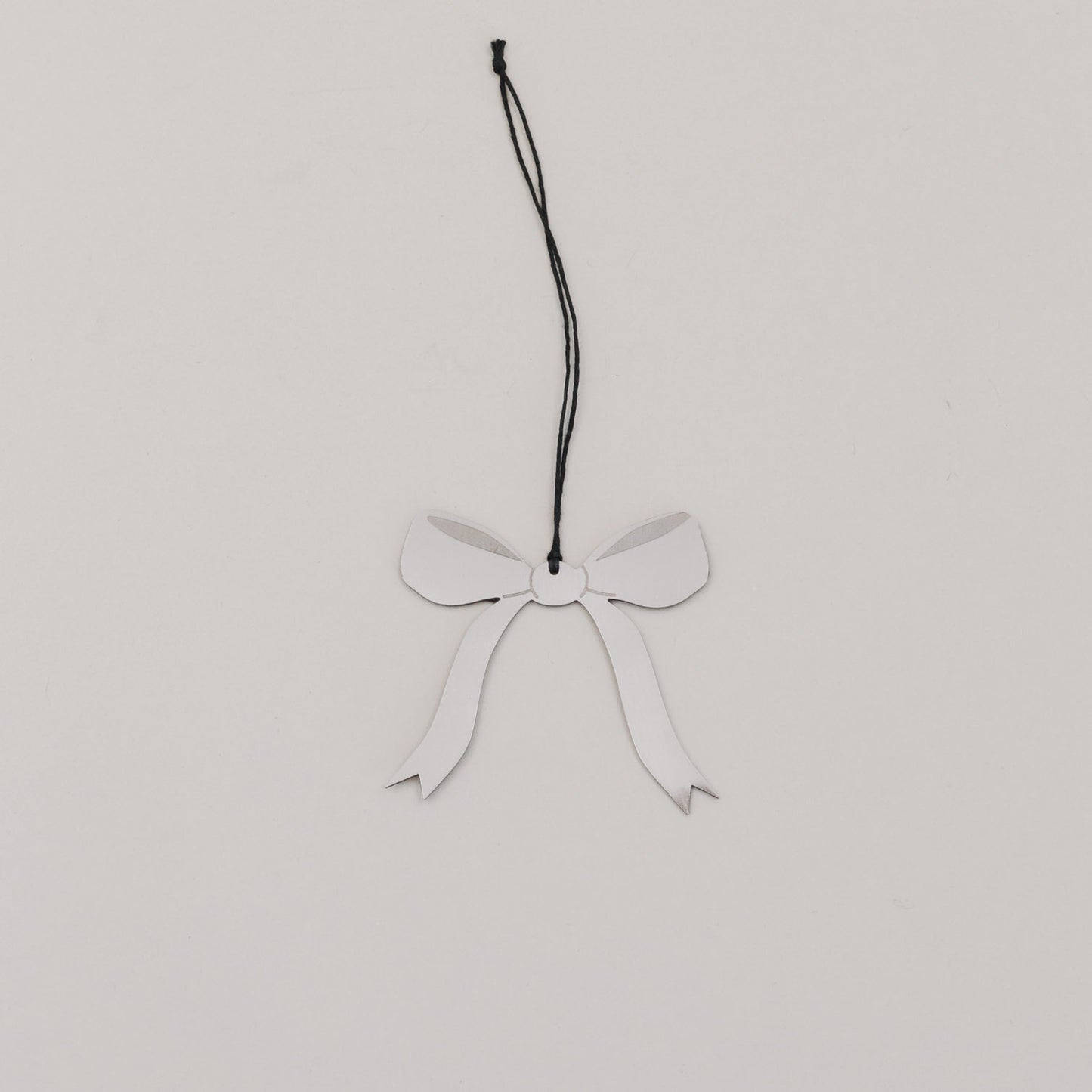 Einzelner Schleifenanhänger aus silberfarbenem Metall mit schwarzem Band auf hellem Untergrund.