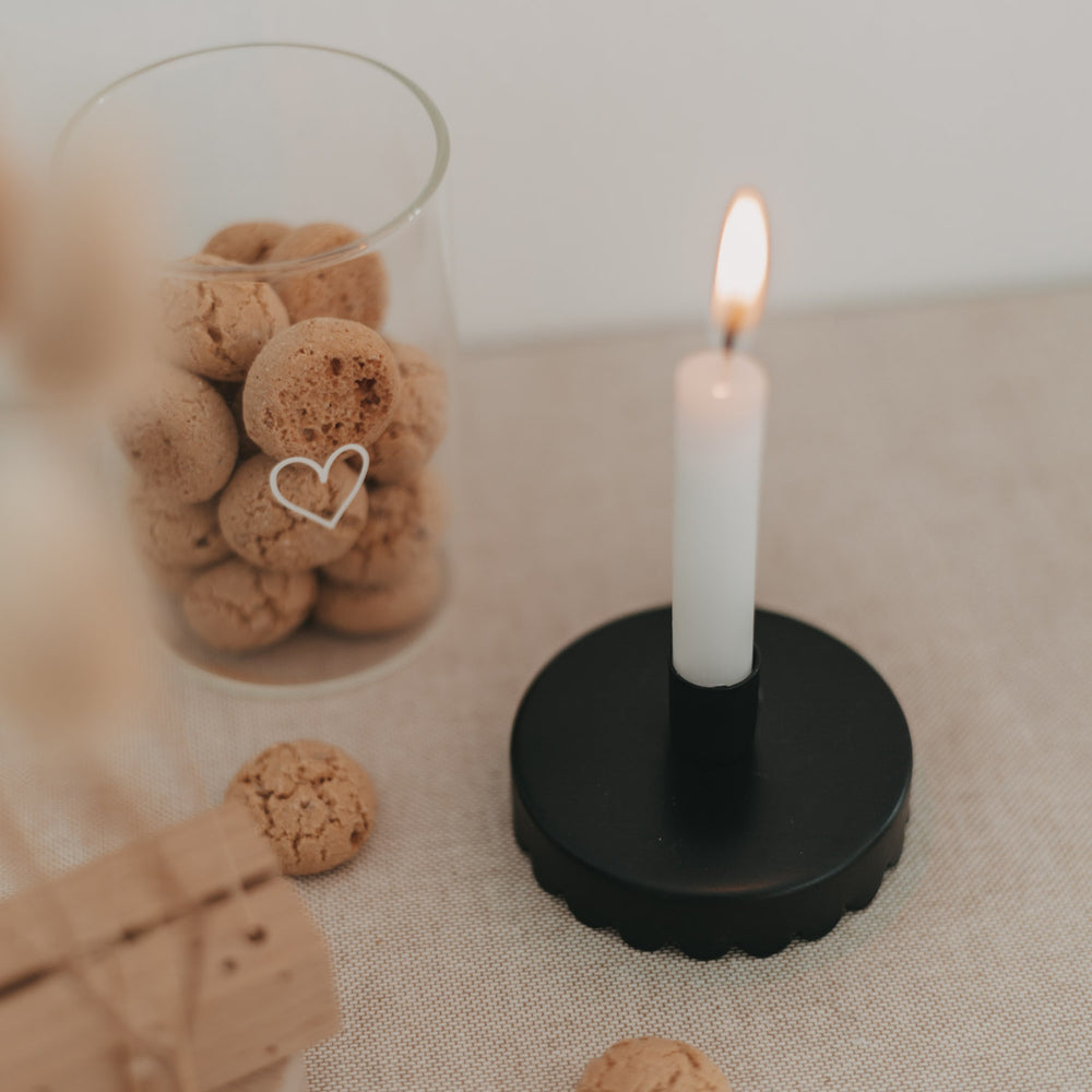 Schwarzer Kerzenhalter Welle als Tischlicht, daneben Vorratsglas mit Gebäck und Herzmotiv.