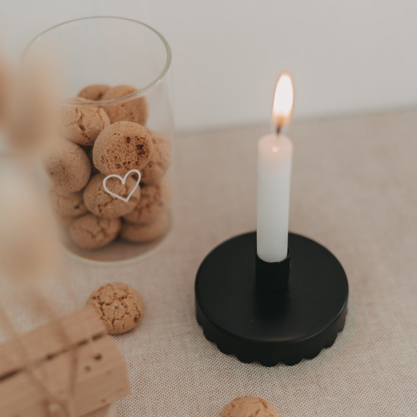 Schwarzer Kerzenhalter Welle als Tischlicht, daneben Vorratsglas mit Gebäck und Herzmotiv.