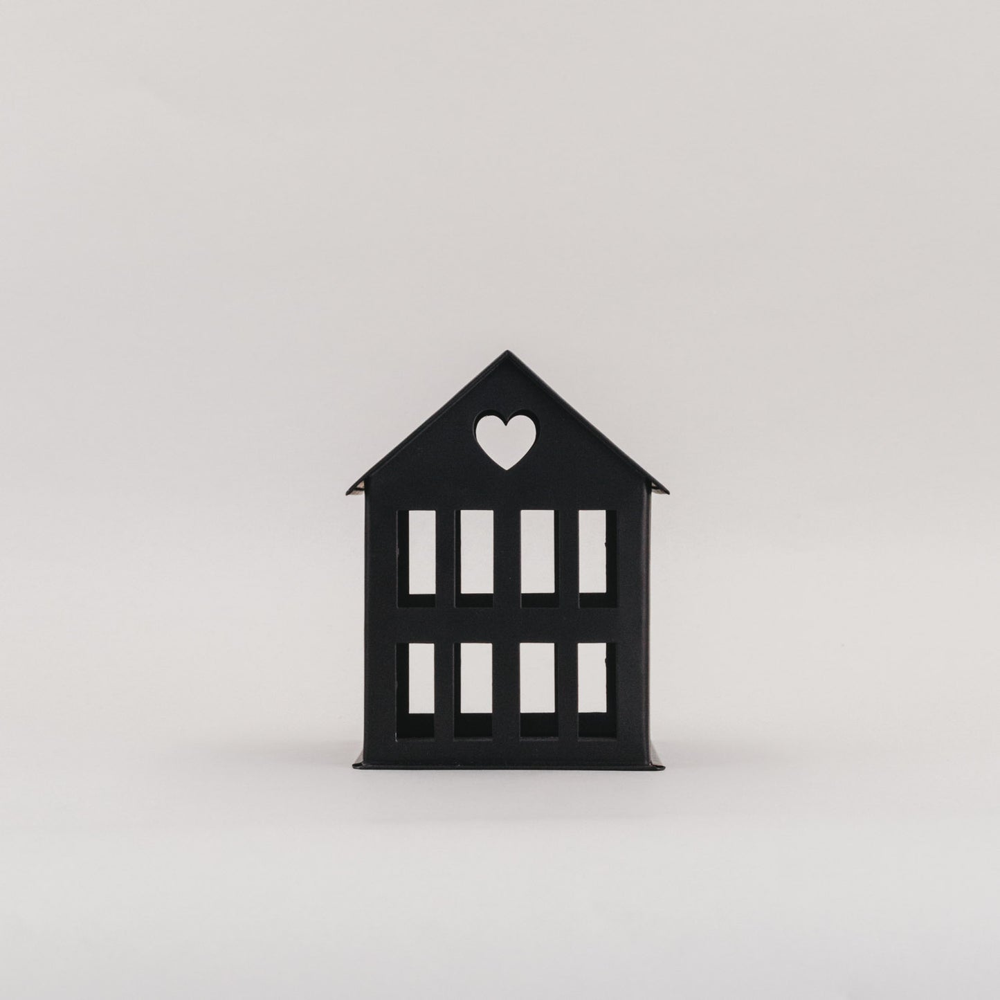 Schwarzes Metallhaus Mini mit Herz im Dach vor hellem Hintergrund – schlichtes Dekoelement aus Metall.
