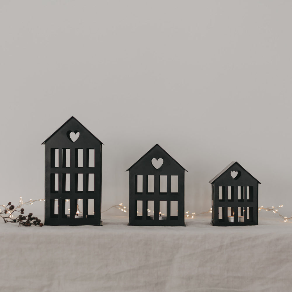 Schwarze Metallhäuser in drei Größen mit Herzmotiv – elegante Tischdekoration mit Lichterkette.