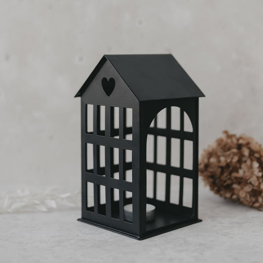 Metallhaus Mittel Schwarz mit Herz im Dach und Teelicht, modernes Dekoelement auf hellem Untergrund.