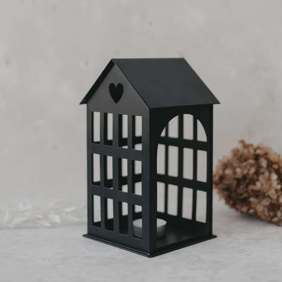 Metallhaus Mittel Schwarz mit Herz im Dach und Teelicht, modernes Dekoelement auf hellem Untergrund.