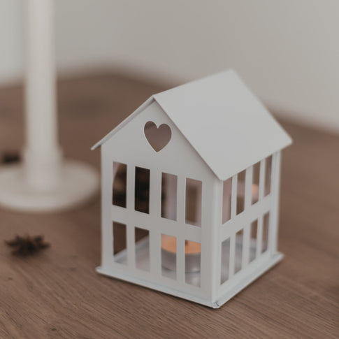 Nahaufnahme des beleuchteten Metallhauses Mini Weiß mit Herz im Dach, warme und schlichte Winterdeko.