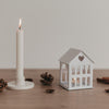 Metallhaus Mini Weiß neben Kerze und Tannenzapfen – festliche Deko für dein Zuhause.