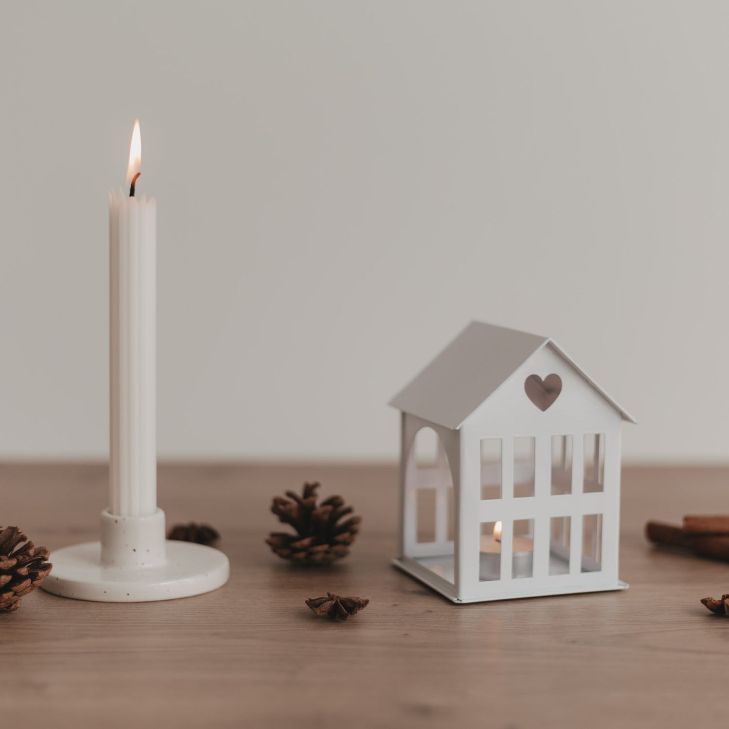 Metallhaus Mini Weiß neben Kerze und Tannenzapfen – festliche Deko für dein Zuhause.
