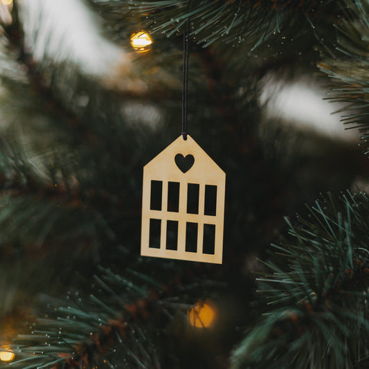 Goldener Hausanhänger  mit schwarzem Band an grünem Tannenzweig.