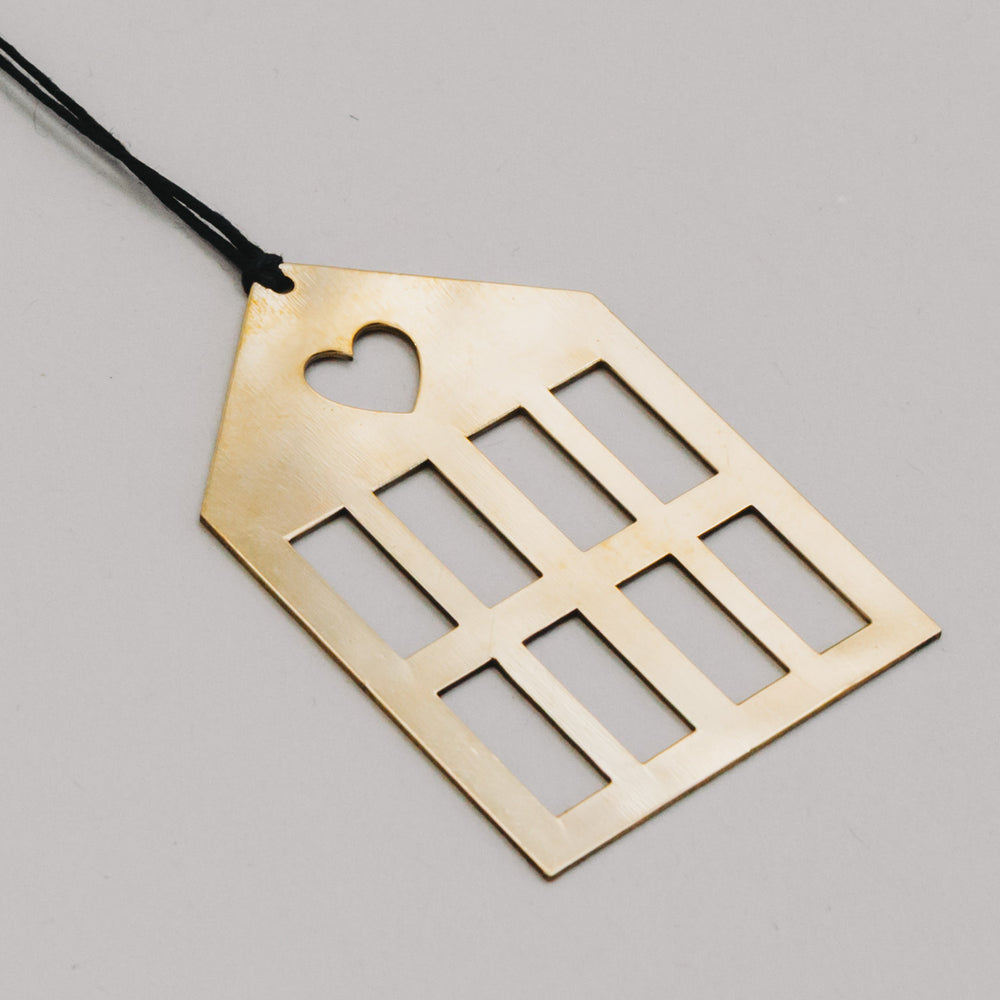 Detailaufnahme vom goldenen Metallhaus mit schwarzer Schnur, zeigt reflektierende Oberfläche.