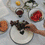 GIF zeigt den weißen Emaille-Speiseteller mit schwarzem Herz im sommerlichen Picknick-Setting mit Weintrauben und weiterem Emaille-Geschirr.