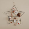 Adventskalender Stern groß aus Metall, dekoriert mit Geschenken, Karten und Anhängern an der Wand