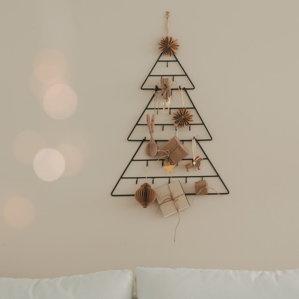 Kleiner Adventskalender Tanne aus Metall an der Wand, stilvoll dekoriert mit Geschenken und Anhängern