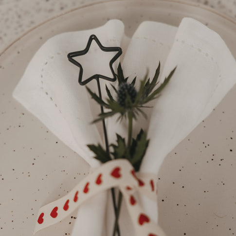 Anthrazitfarbener Stern Metallstecker als weihnachtliche Serviettendeko mit Distel und Herzband