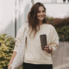 Frau unterwegs mit braunem To-go-Thermobecher mit Herzmotiv und Stofftasche