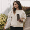 Frau mit braunem To-go-Thermobecher mit Herzmotiv und schwarzem Deckel